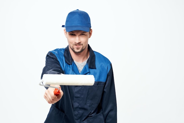 A man in a working uniform a roller for painting walls in his hands decoration repair