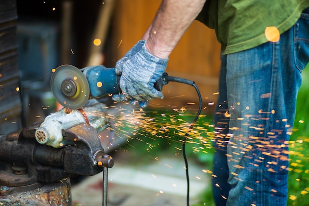 Man working with grinder saw close up view on tool Electric saw and hands of worker with sparks Worker cutting metal with grinder