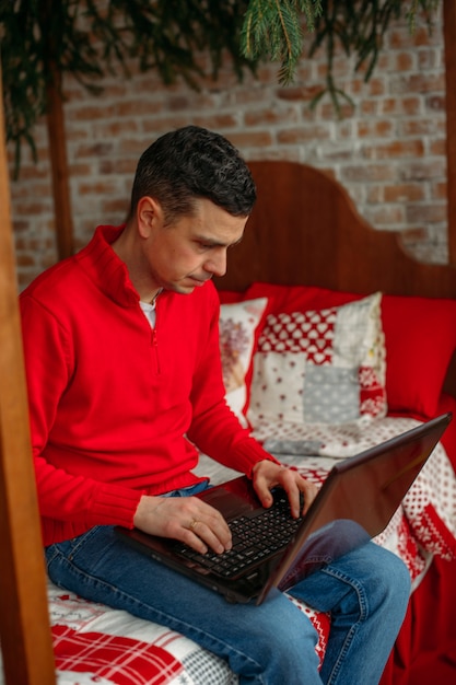 Man working with laptop in bedroom