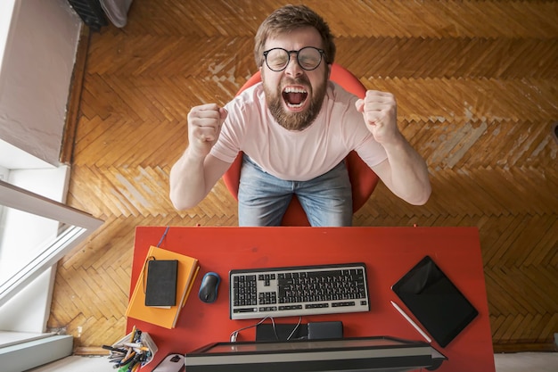 Man works at home He experiences stress and overwork nervously clenches fists and screams