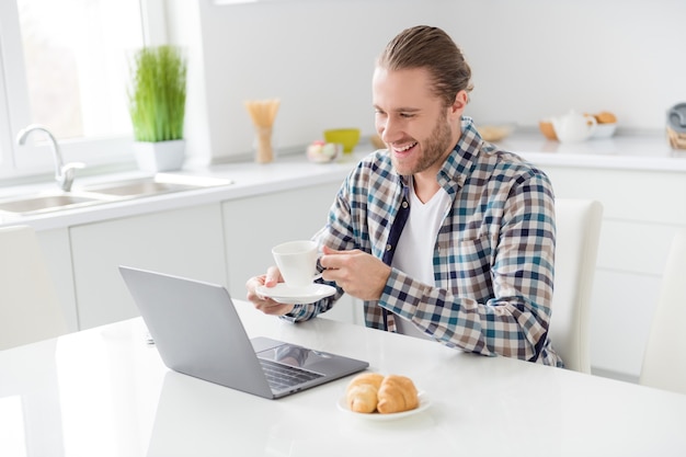 man works on laptop and drinks coffee