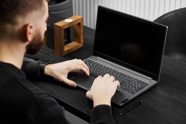 A man works at a laptop on a gray table a mockup