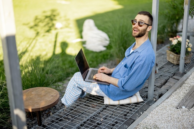 Photo man works on laptop while sitting at backyard