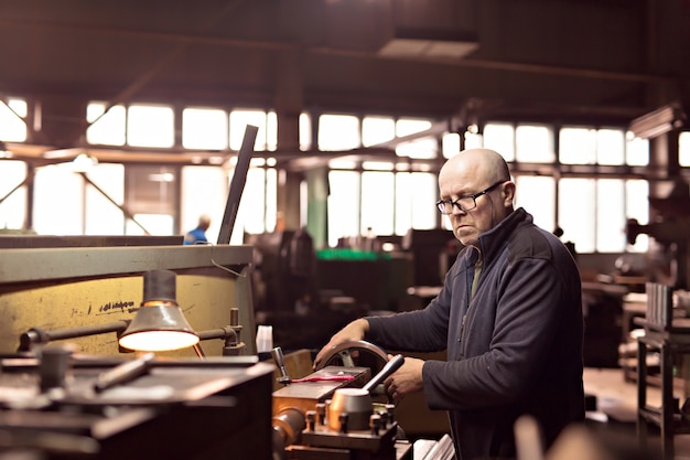 A man works at the machine at the factory