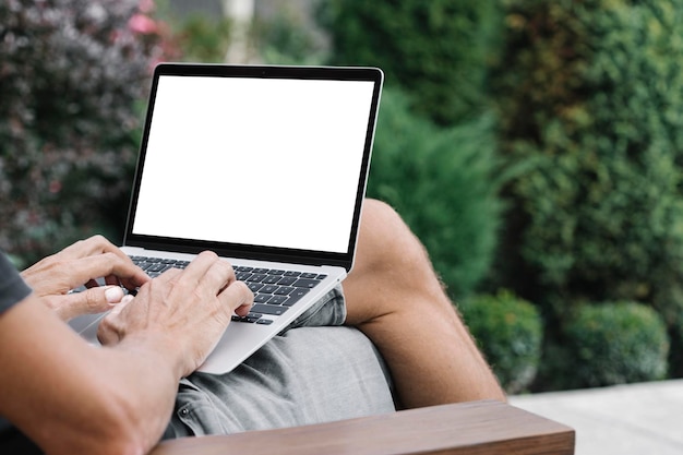 A man works in nature sitting in a chair with a laptop