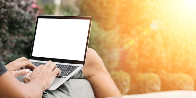 A man works in nature sitting in a chair with a laptop