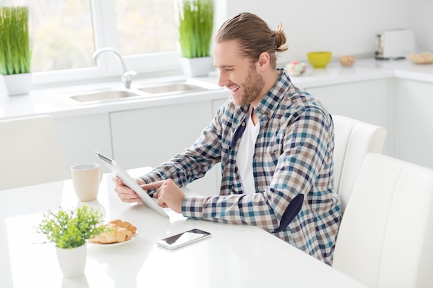 man works on tablet and eats breakfast