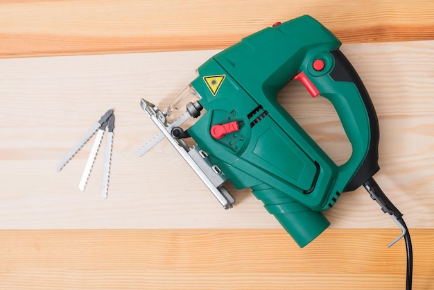 A man works with an electric jigsaw for wood on a wooden table with and without gloves and measures with a tape measure