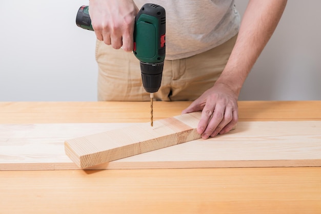 A man works with an electric screwdriver on a wooden table