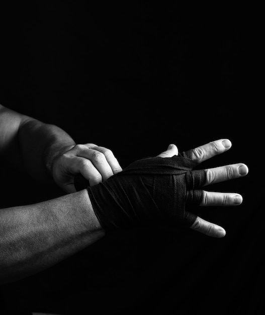 Man wraps his hands in black textile bandage for sports