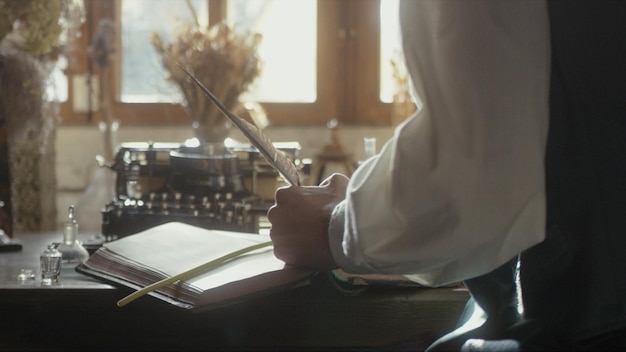 A man writer dips his pen into an inkwell and prepares to write a book in his workshop premium photo