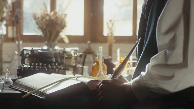 A man writer dips his pen into an inkwell and prepares to write a book in his workshop premium photo