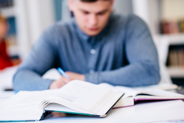 Photo man writing on table with books