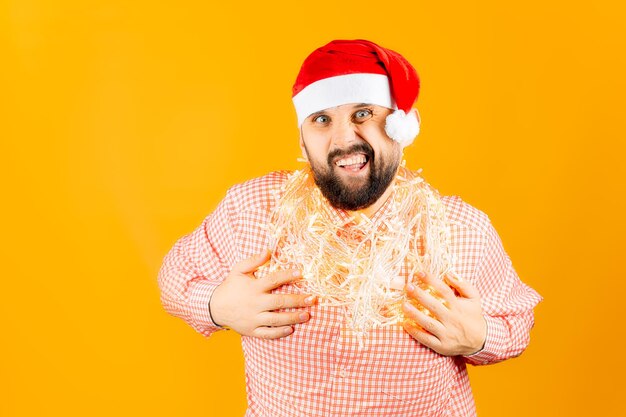 A man on a yellow background in a plaid shirt, department a garland around his neck and shows gestures