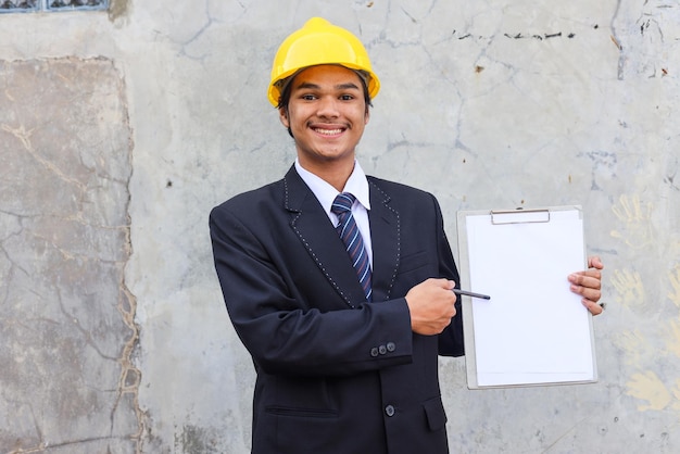 A man in a yellow helmet holds a white board with the word " build " on it.