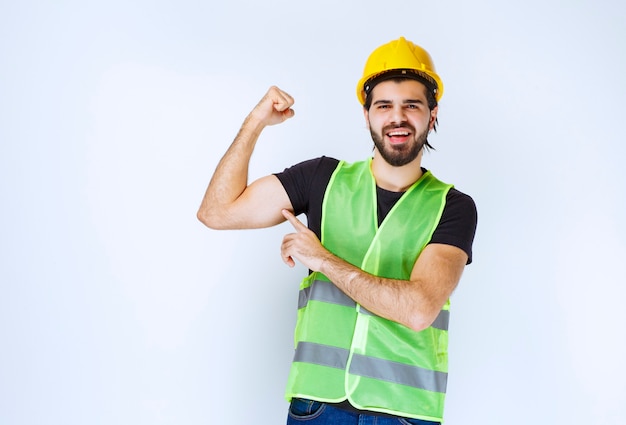 Man in yellow helmet showing his arm muscles.