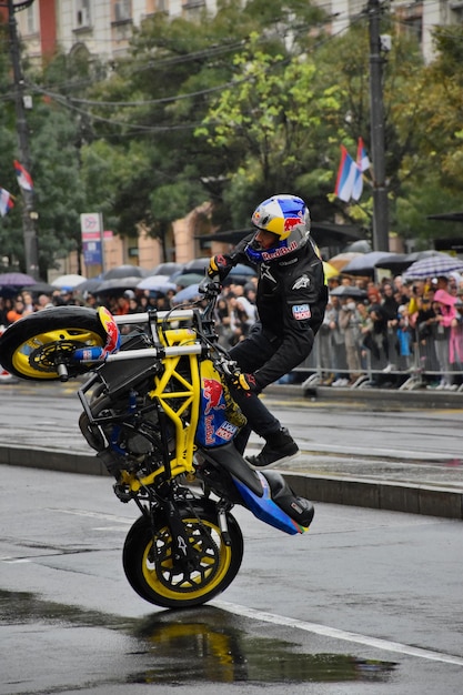 Photo a man on a yellow motorcycle is doing a trick with the number 12 on the front