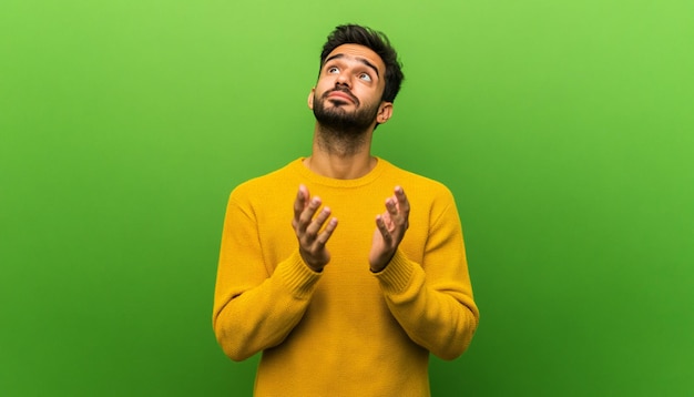 a man in a yellow shirt is looking up and has a green background