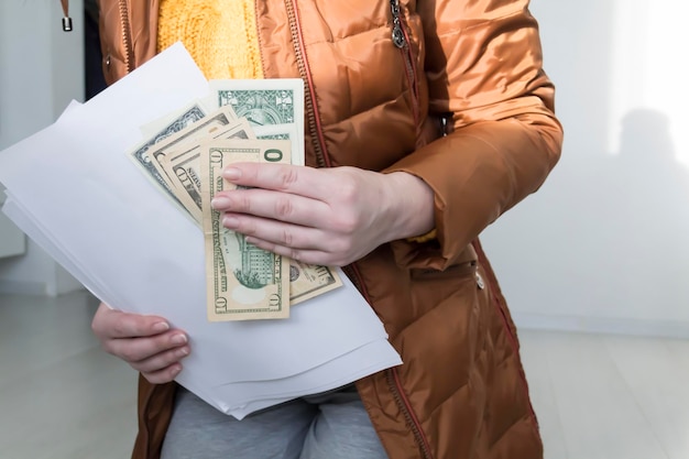 A man in a yellow sweater and jacket with documents in his hands and money The concept of the economic crisis and large utility bills in homes