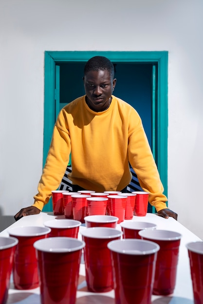 Man in yellow sweatshirt playing beer pong