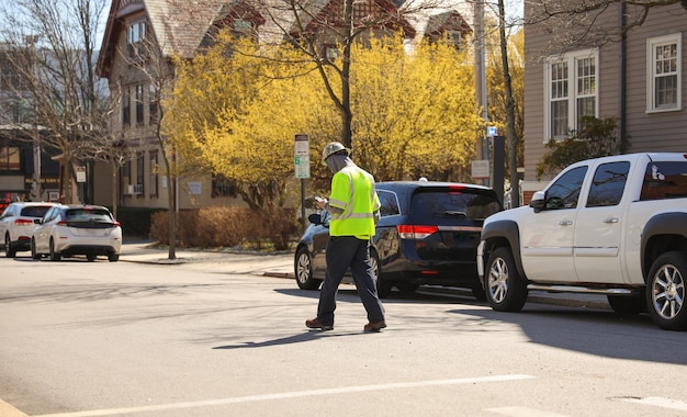 A man in a yellow vest crosses the street in front of a car.