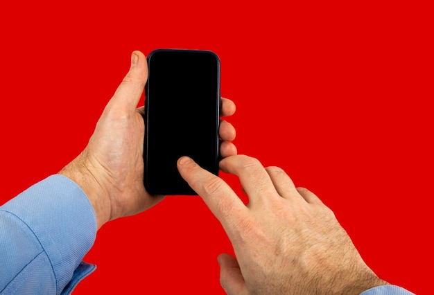 Man39s hand with shirt holding smartphone studio shot red background