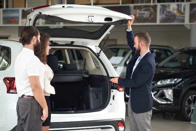 Manager of car center showing to couple cargo space.