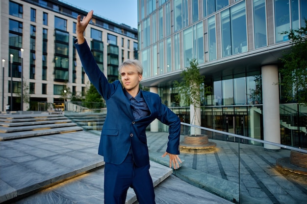 Manager in dark blue business suit stands near office center