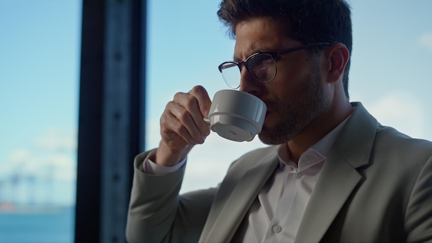 Manager drinking coffee in ocean view office closeup Businessman having break