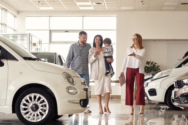 The manager helps the young family choose the most comfortable car for the city.