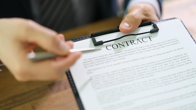 Manager holding out document contract on clipboard and pen for signing closeup