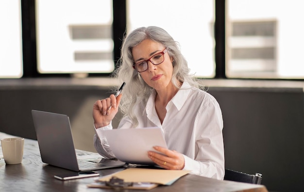 Manager woman reading candidate cv holding paper in modern office