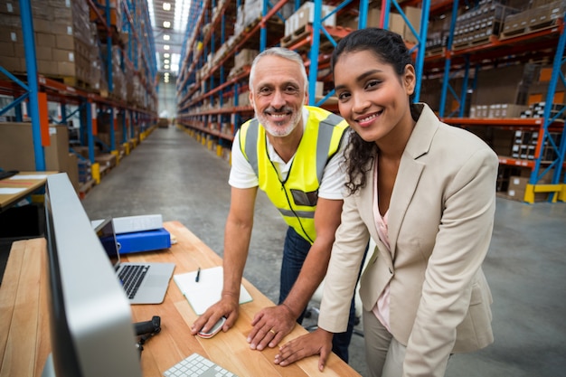 Manager and worker are posing and looking the camera during work on computer