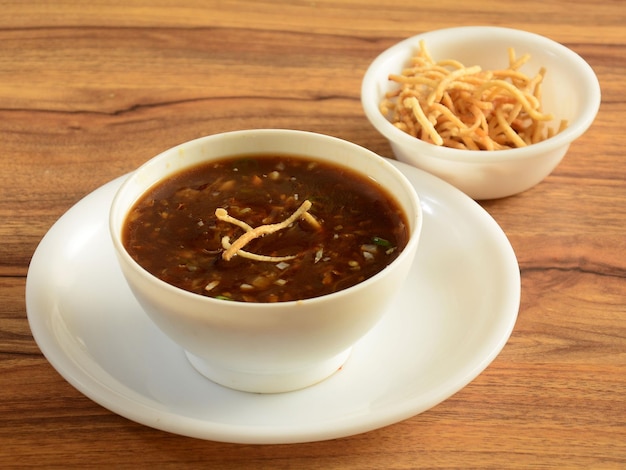 Manchow soup indo chinese dish served over a rustic wooden background selective focus