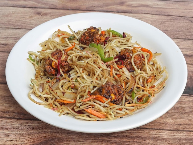 Photo manchurian noodles a popular indochinese dish served over a rustic wooden background selective focus