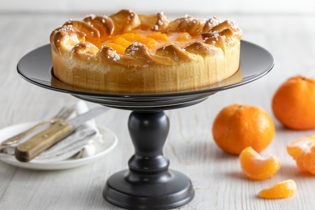 Mandarin cake and tangerines on rustic background, close-up