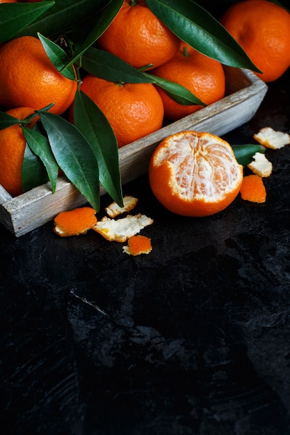 Mandarins with leaves in a box on a dark background