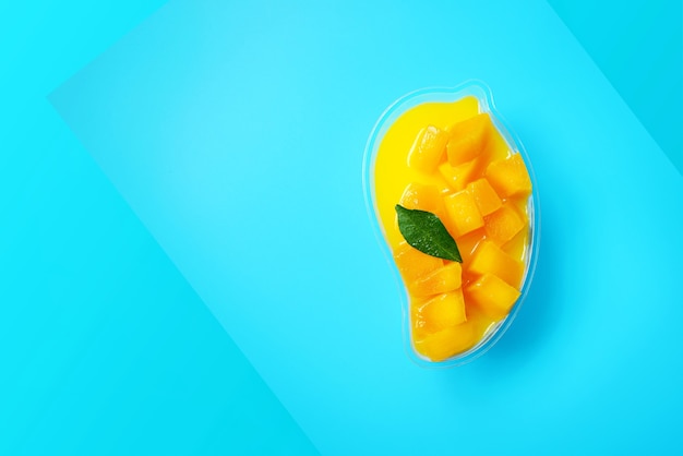 Mango cheesecake top view on blue background with copy space flat lay style