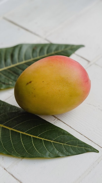 Photo a mango is laying on a white surface with a green leaf