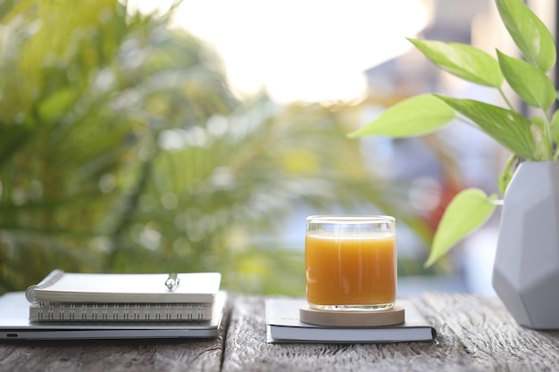 Mango juice and notebooks on wooden table