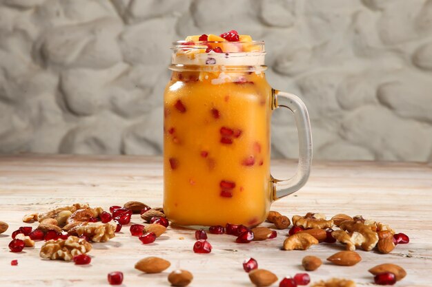 Photo mango juice with nuts pomegranate seeds walnut almond and cashew served in jar isolated on background top view of healthy morning drink