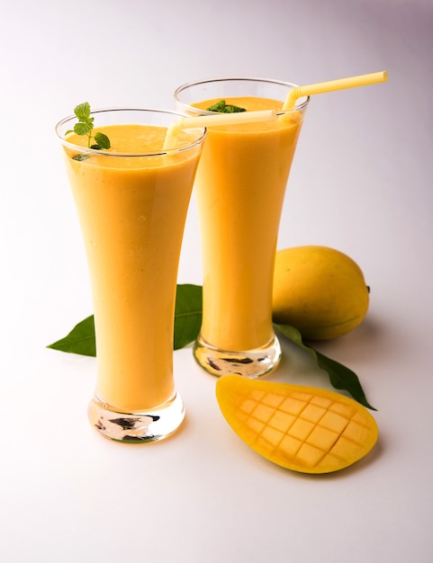 Mango Lassi or yogurt, Indian popular summer drink served in glass with whole Alphonso Aam fruit, selective focus