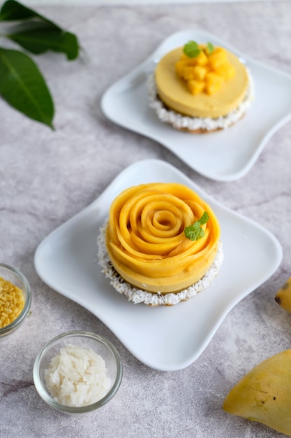 Mango Mousse tart with sticky rice and fresh mango. set on white cafe table.