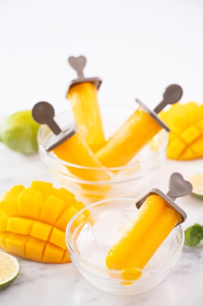 Mango popsicle fruit ice in the plastic shaping box on bright marble table Summer refreshment concept product design elements objects close up