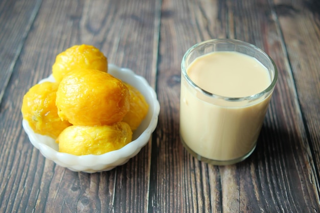 Mango smoothie and fresh mango on wooden background