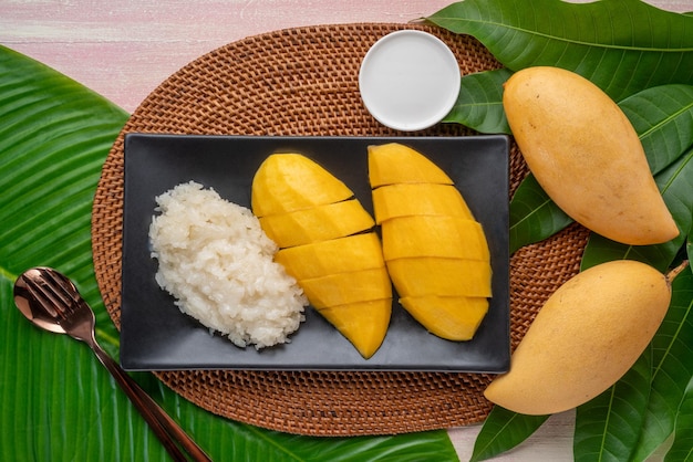 Mango with sticky rice on black plate Yellow mango with sticky and coconut milk a Thai dessert