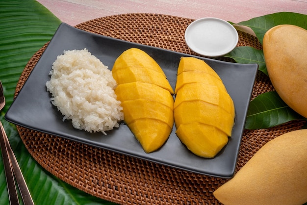 Mango with sticky rice on black plate Yellow mango with sticky and coconut milk a Thai dessert