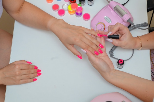 Manicure  Beautiful wellgroomed female nails with bright pink nail polish in the salon