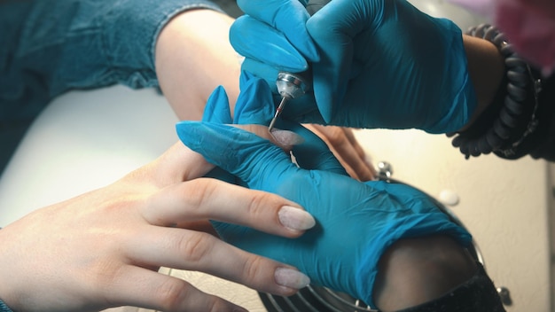 Manicure master doing manicure cleans the cuticle using hardware device