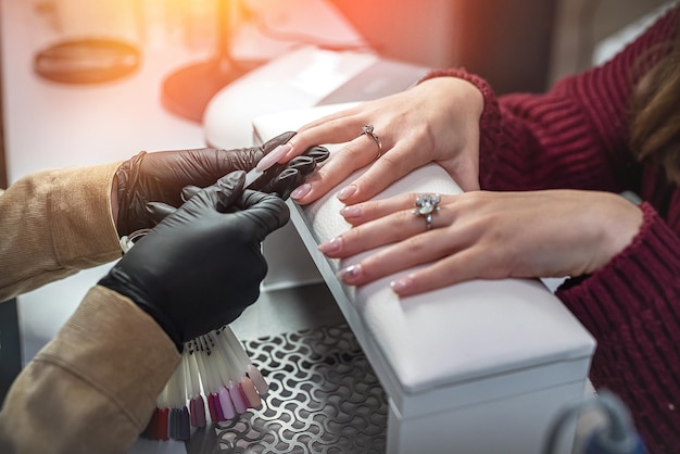 Photo manicure master with client in beauty salon chooses color of gel polish manicure concept